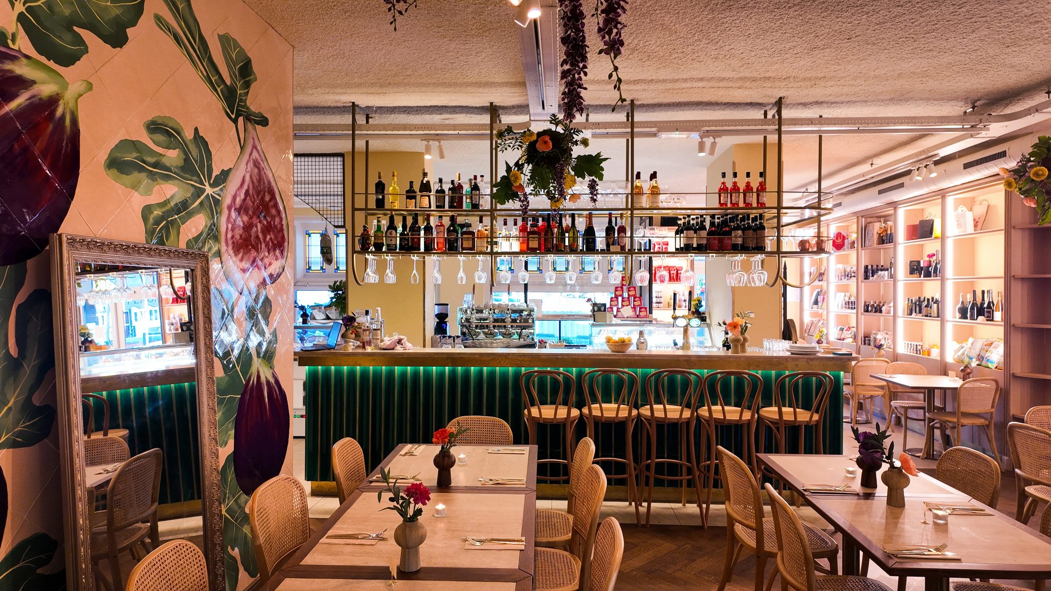De osteria van Il Fico met gedekte tafels, de groene bar en een muurschildering van vijgen