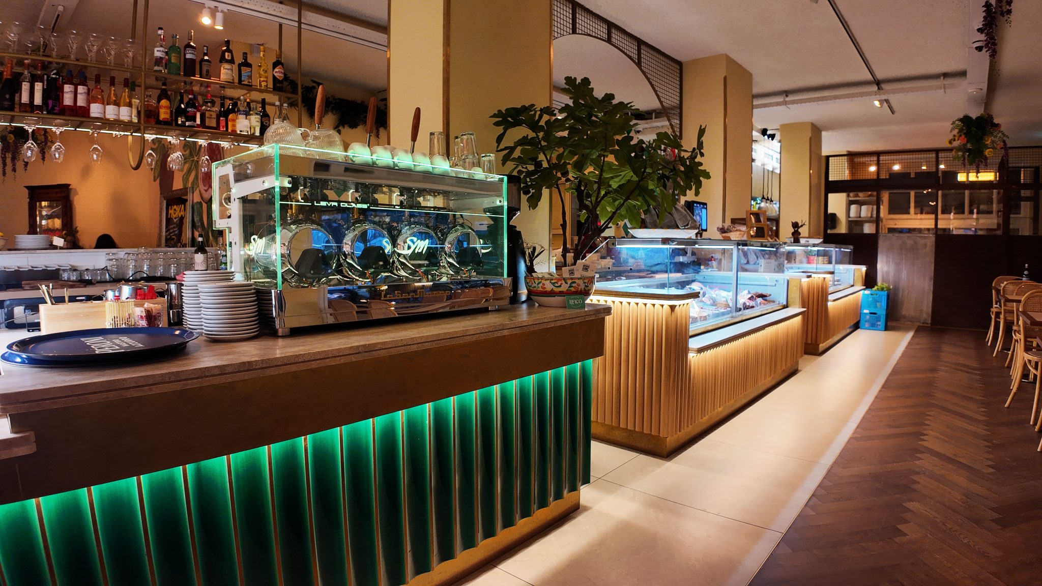 De bar van Il Fico met espressomachine, glazen vitrines en een houten visgraatvloer