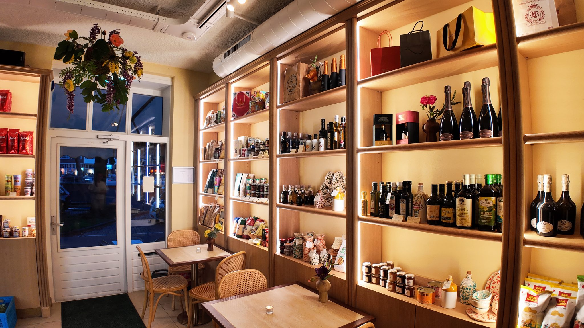 Verlichte wandkasten vol Italiaanse wijnen, olijfolie en delicatessen in de winkel van Il Fico